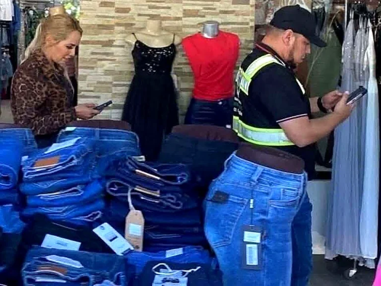 洋服店のジーンズ売り場に立つ、ベスト姿の男性の写真