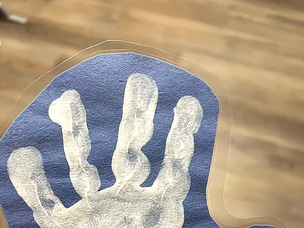 青い画用紙に押された、子供の白い手形の写真
