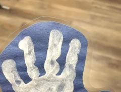 青い画用紙に押された、子供の白い手形の写真