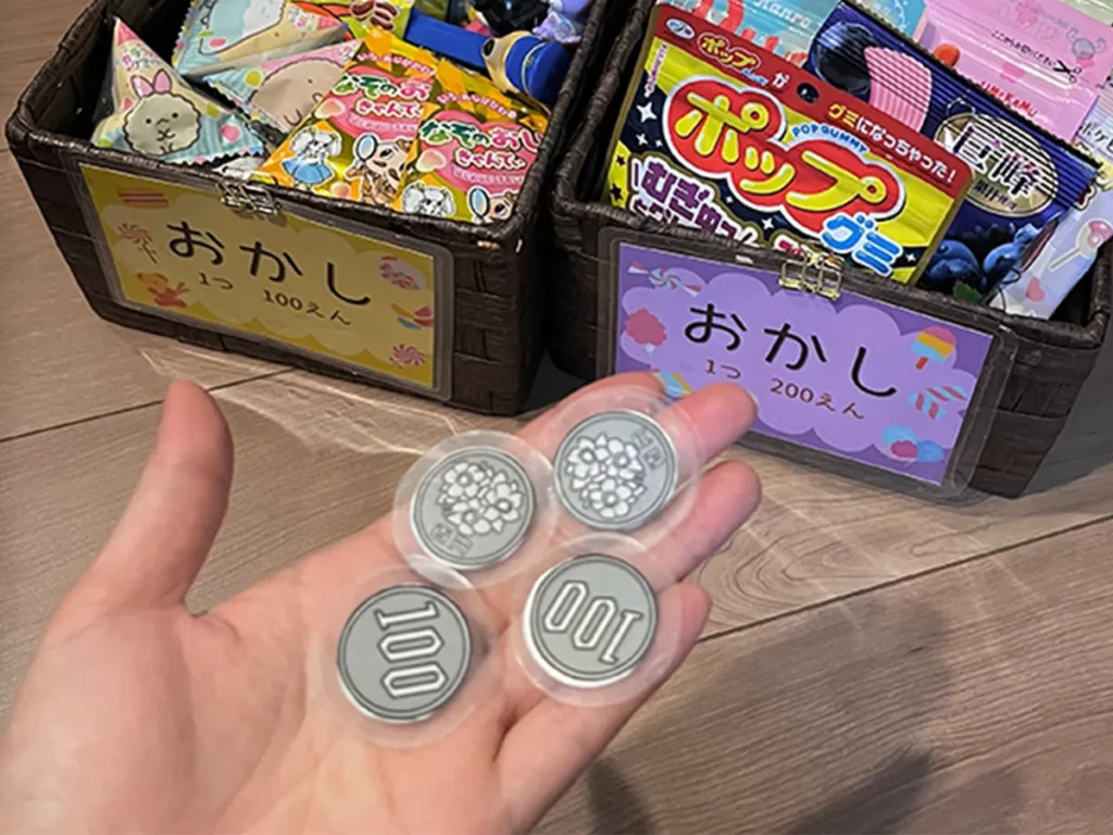 箱に入ったお菓子と手作りの100円玉の画像