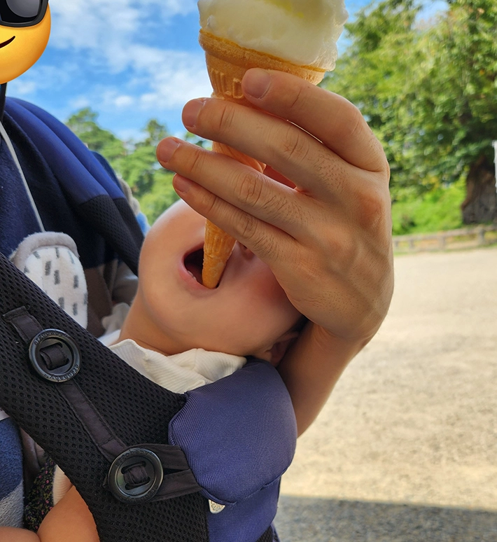 下からアイスのコーンを食べる子供の画像